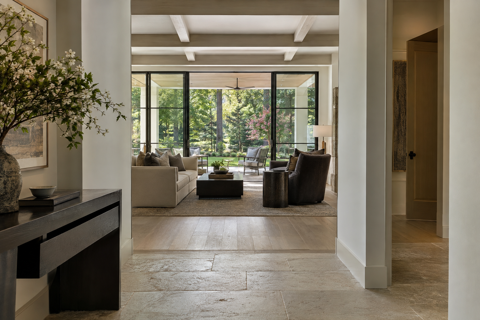 A limestone-floored foyer opens toward a white oak living room and covered terrace, with an offset passage beside the main circulation route.